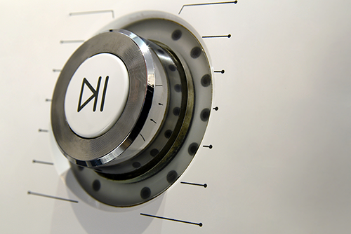 Close-up of a circular metal safe dial with a white center logo, mounted on a light-toned door.